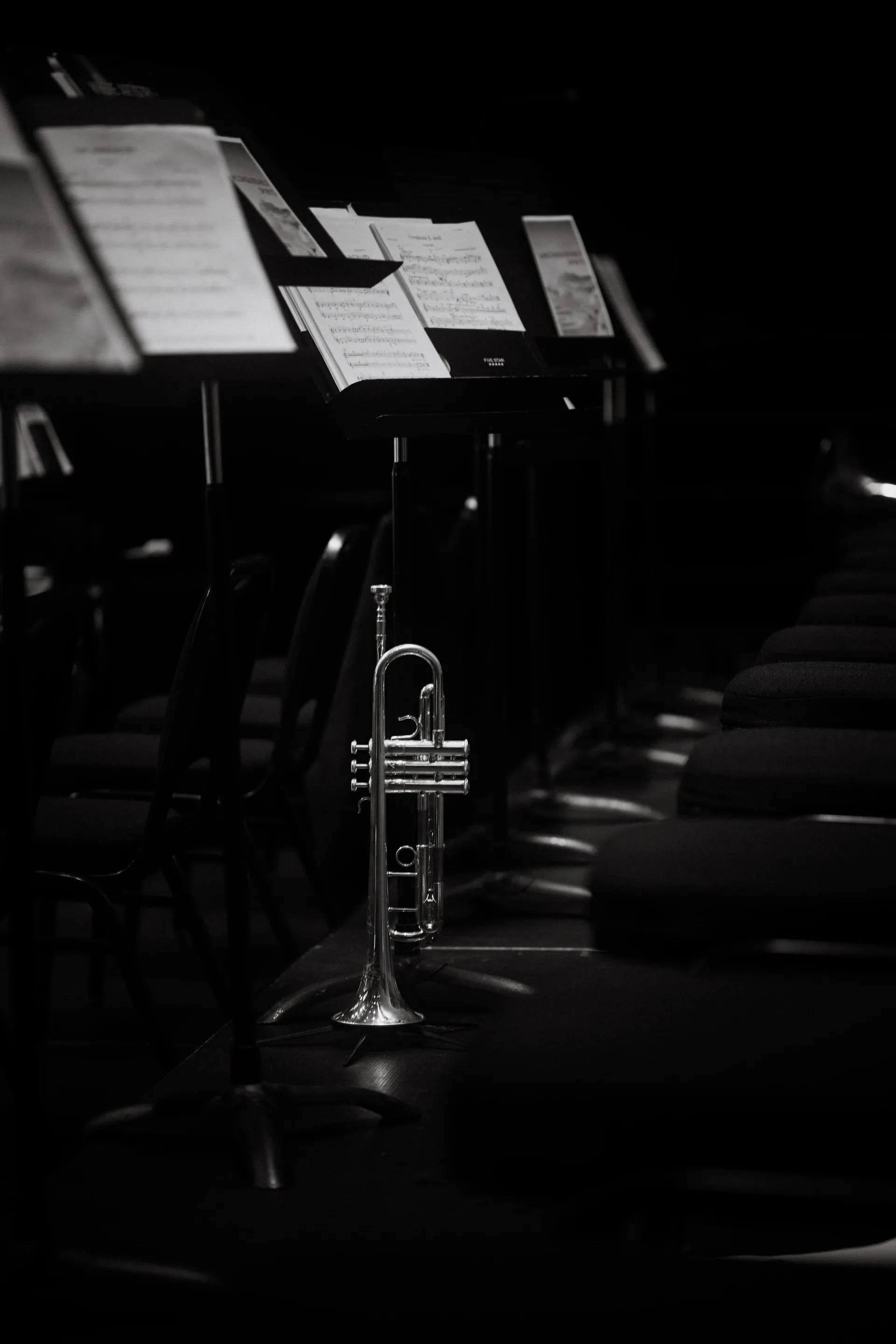 Trombone rests beside empty chairs and illuminated music stands.