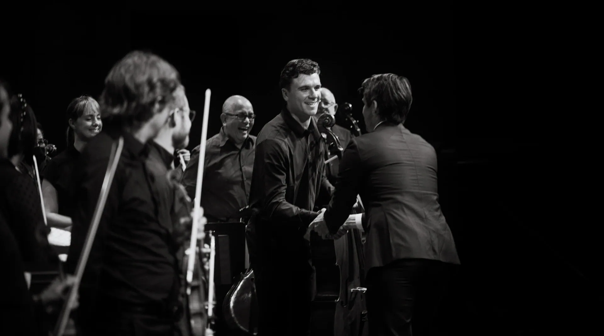 Orchestra musicians greet one another onstage after the performance.