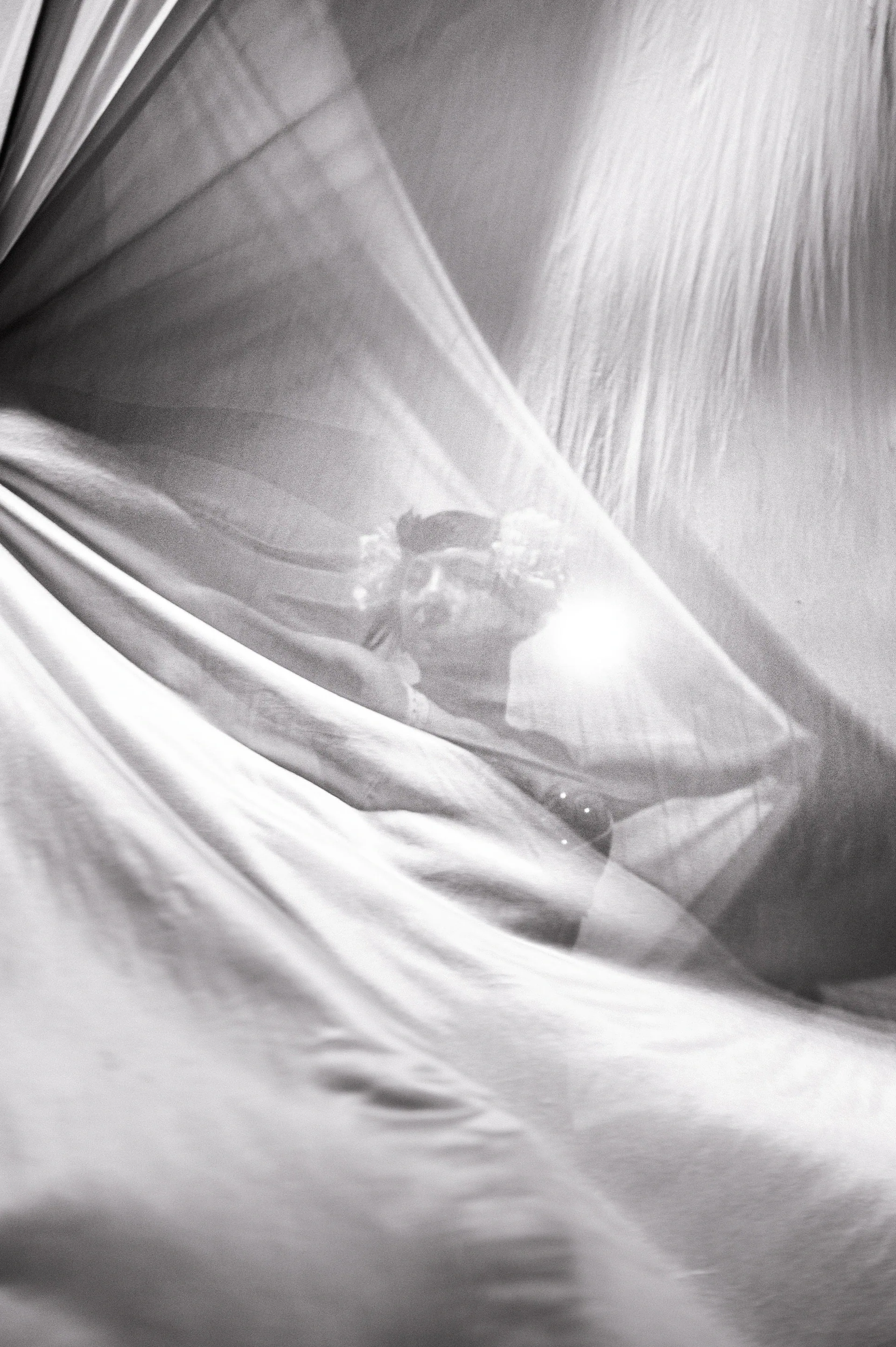 Silhouetted performer is visible through layers of translucent fabric.