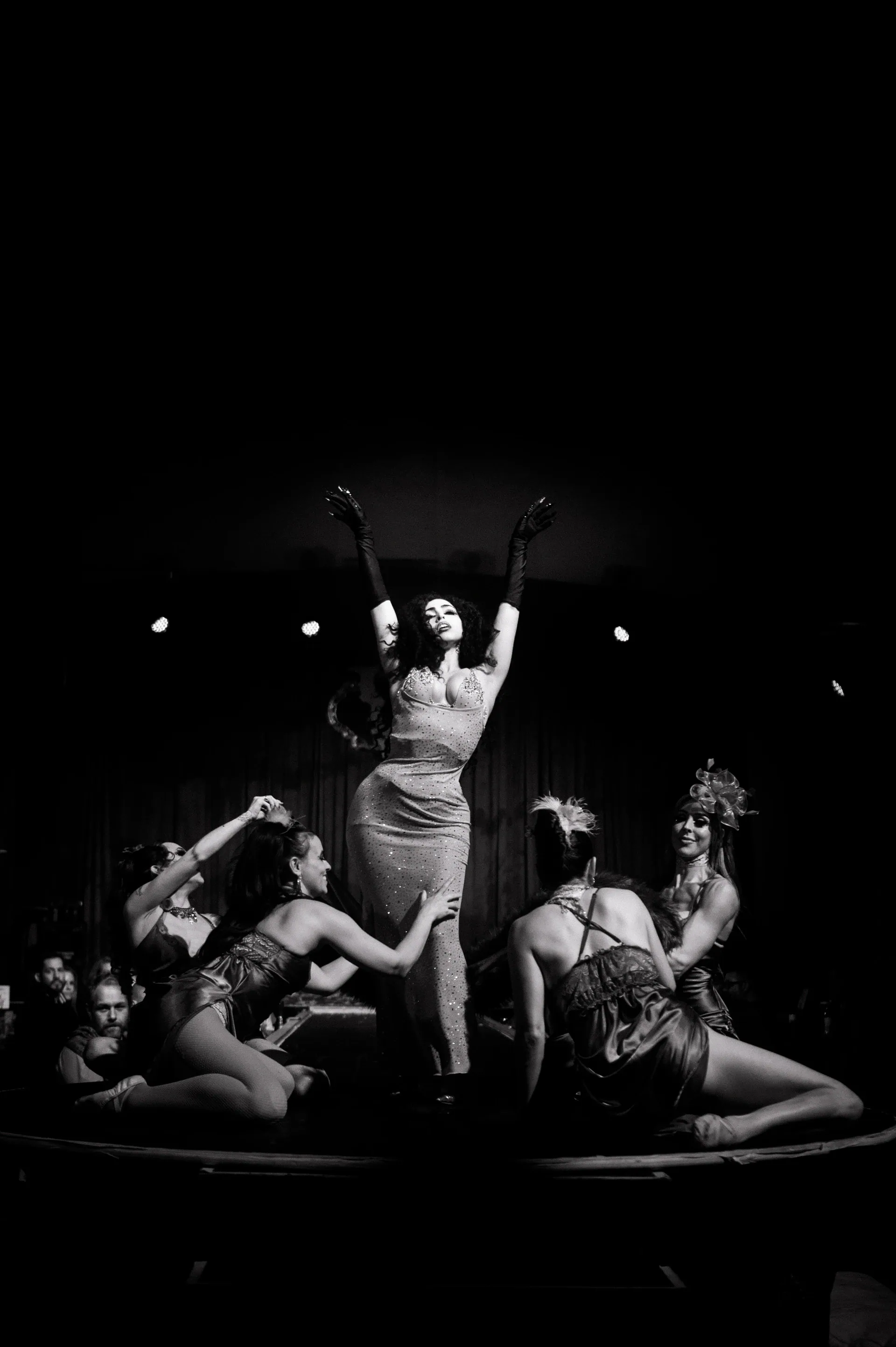 Ensemble of performers poses together with one figure raising an arm.