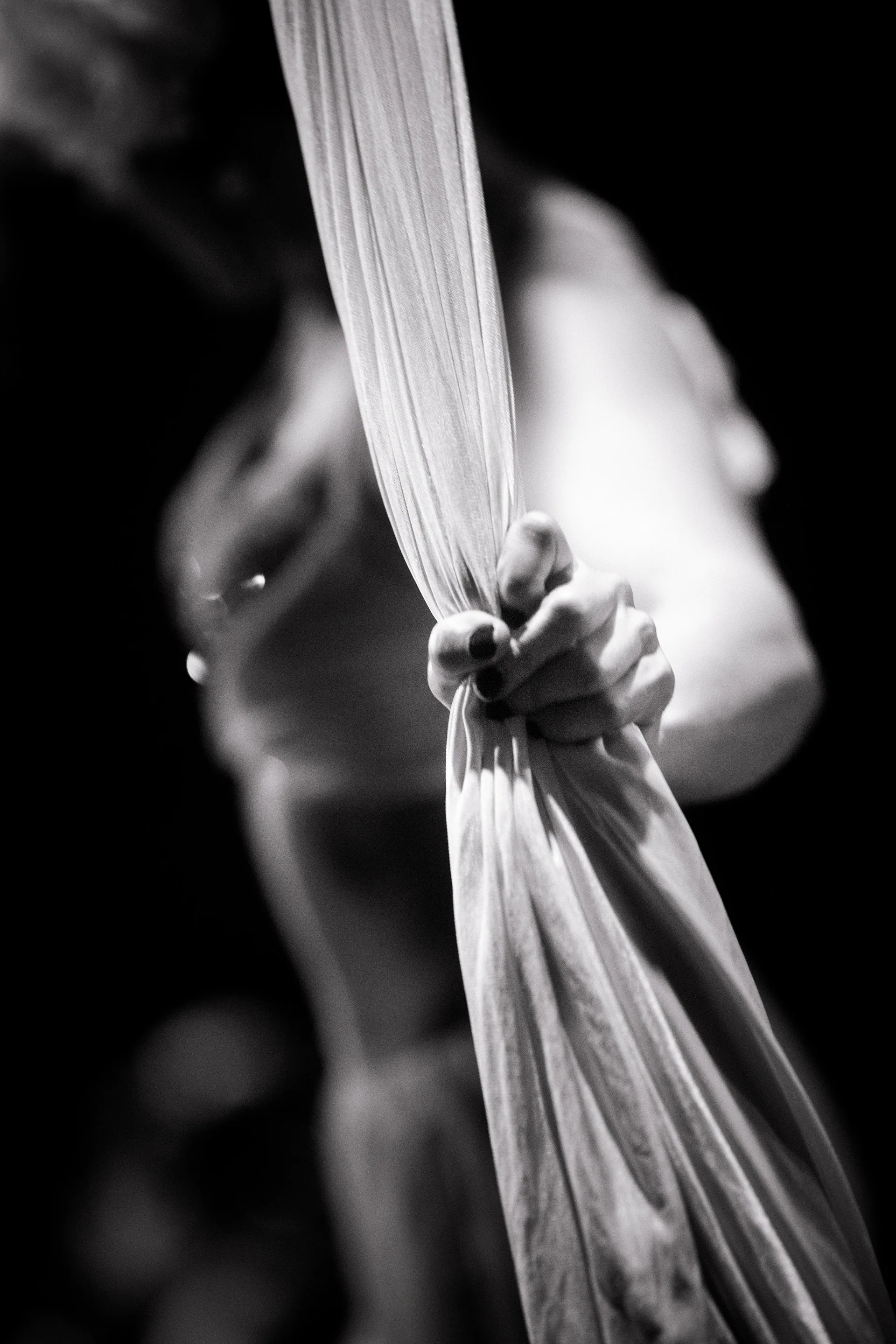 Close view of a hand gripping gathered aerial silk.