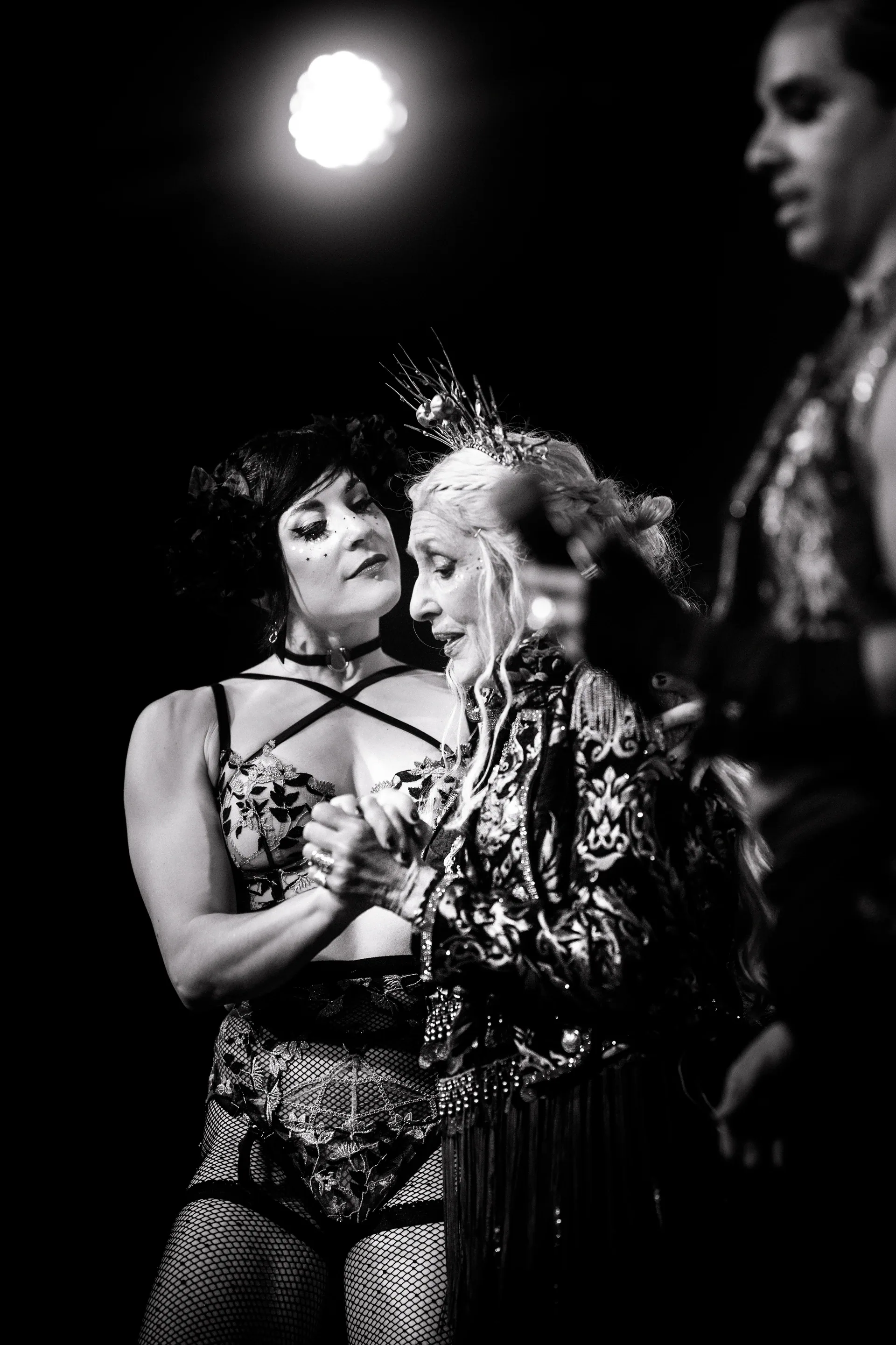 Two costumed performers stand close together while one speaks to the other.