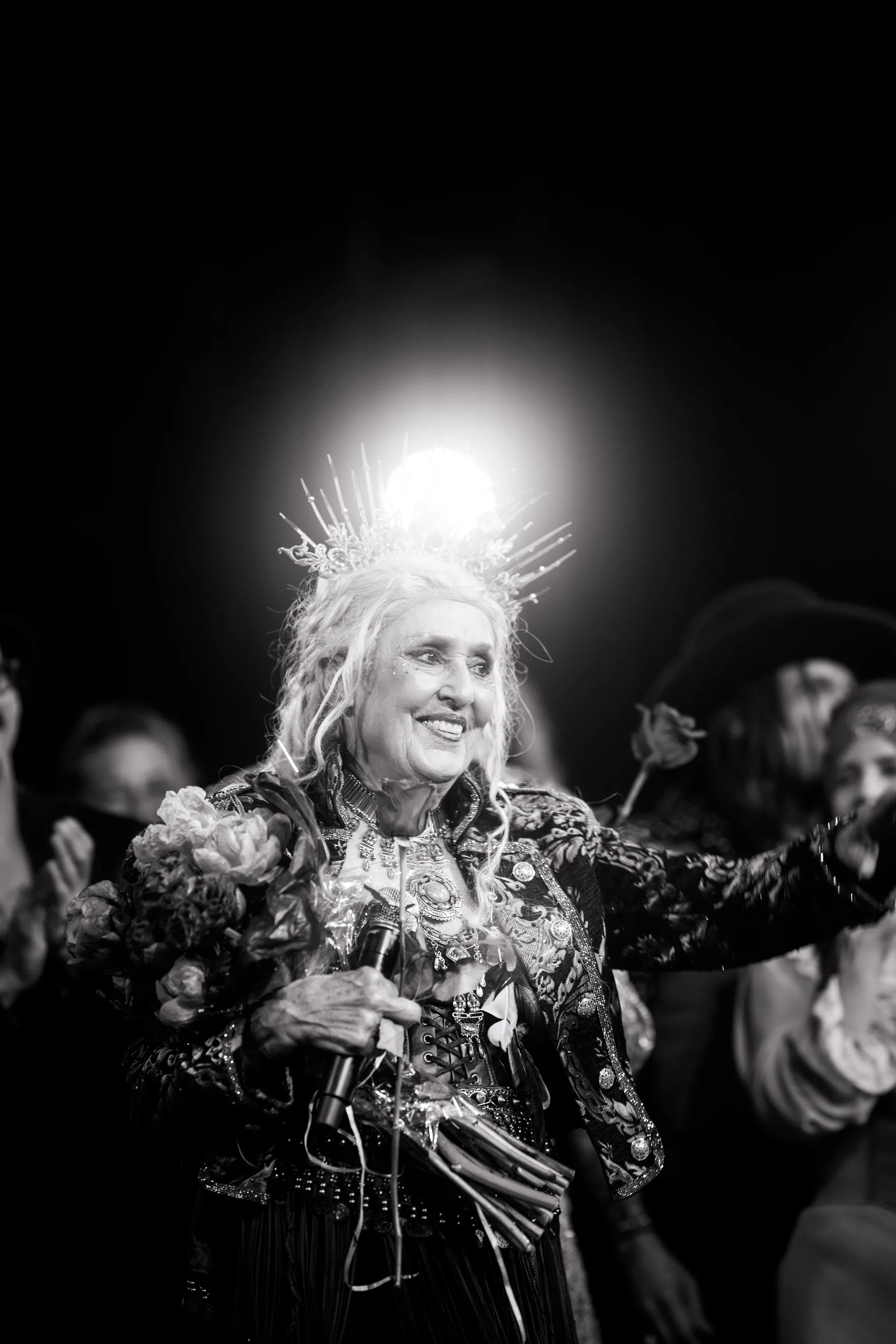 Two elaborately costumed performers smile close together.