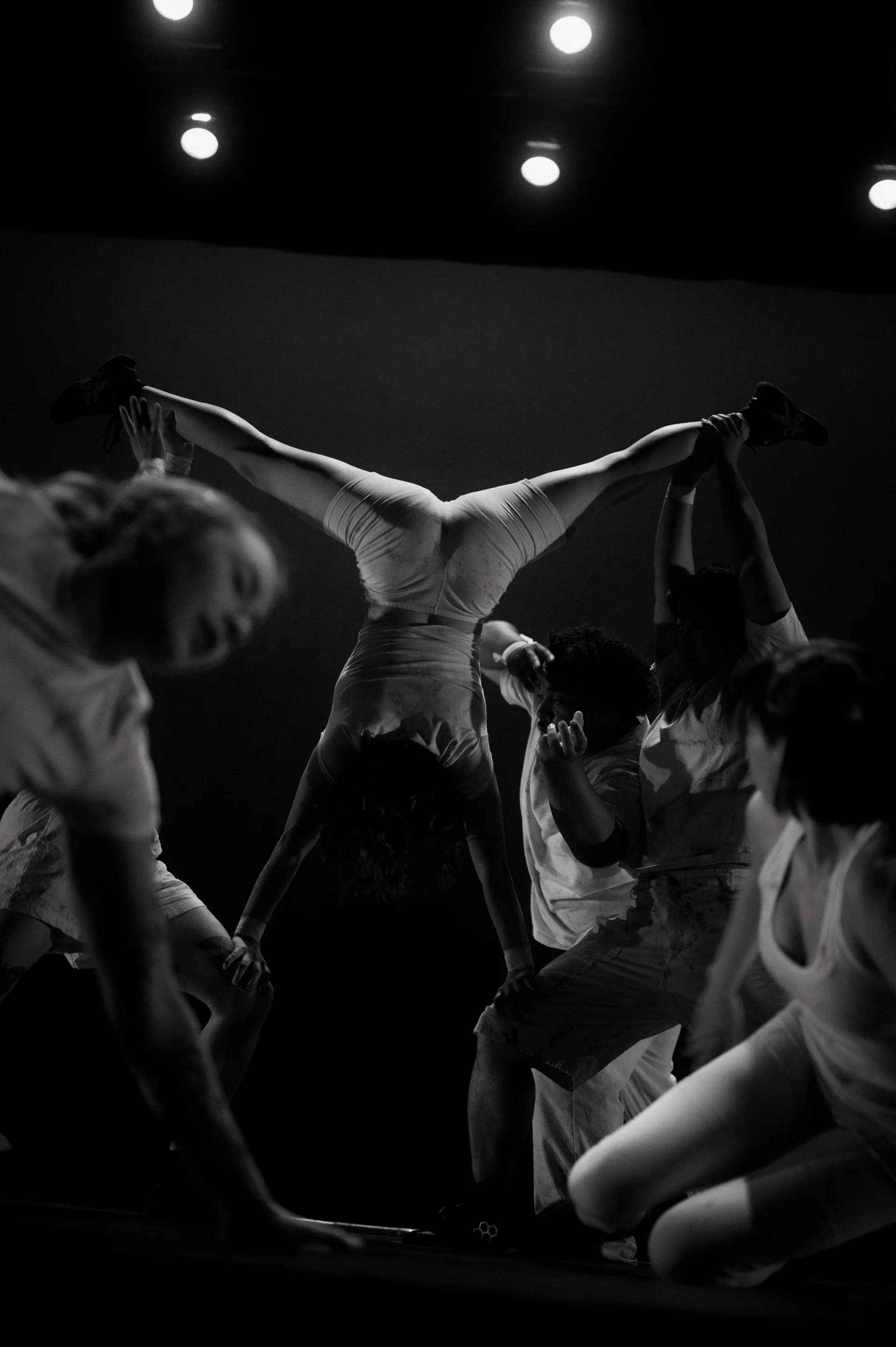 Performer extends horizontally above a kneeling group.