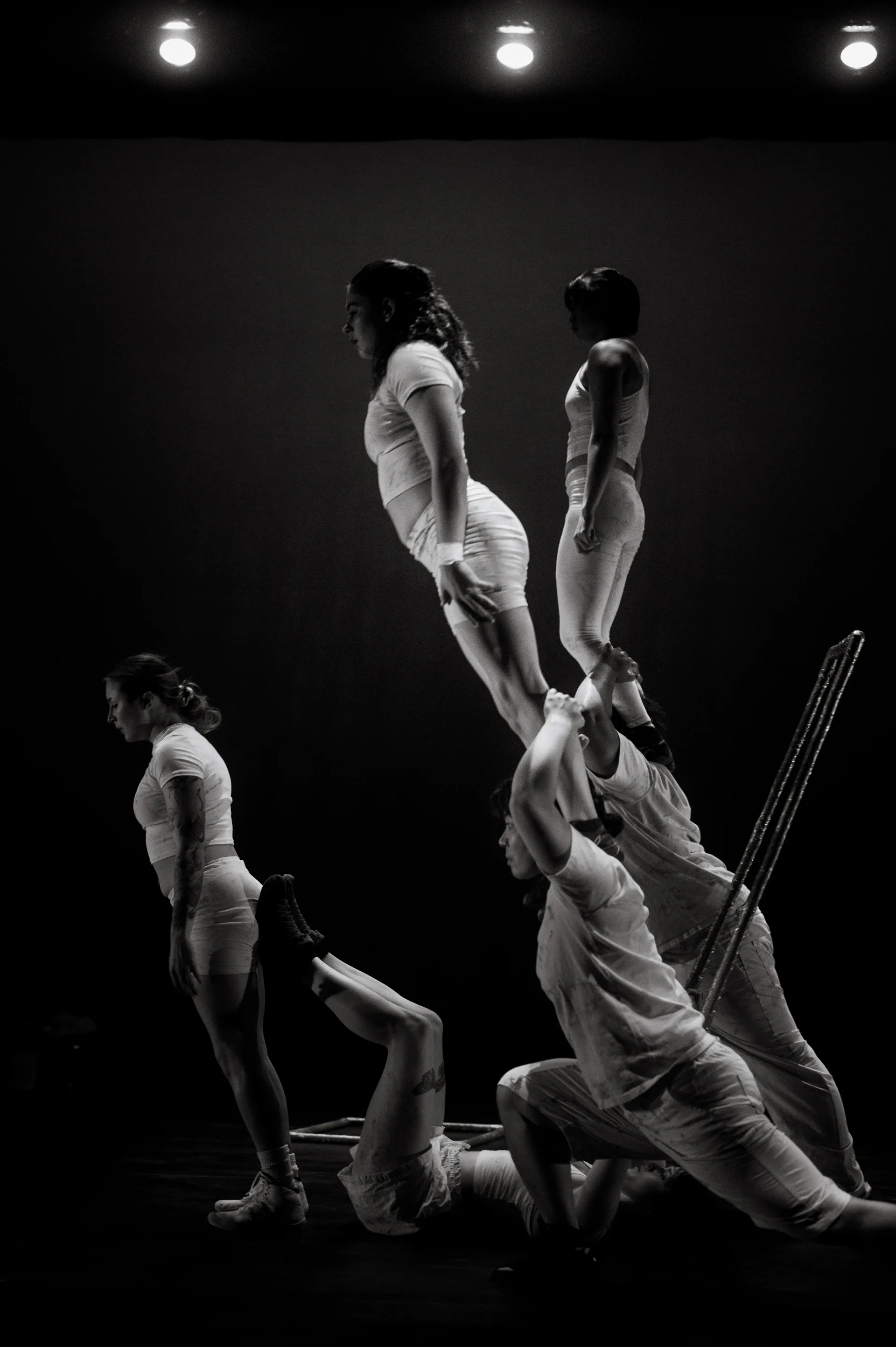 Group balances two standing performers on the shoulders of others.