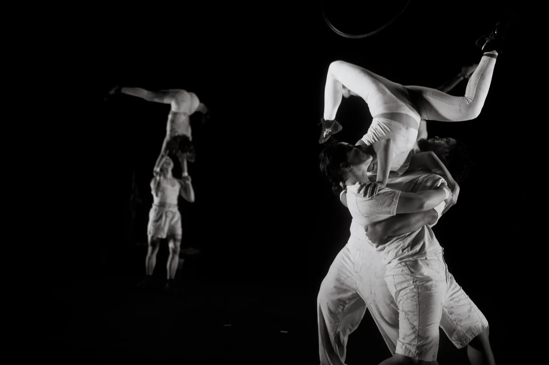 One acrobat curves backward over a partner's shoulders.