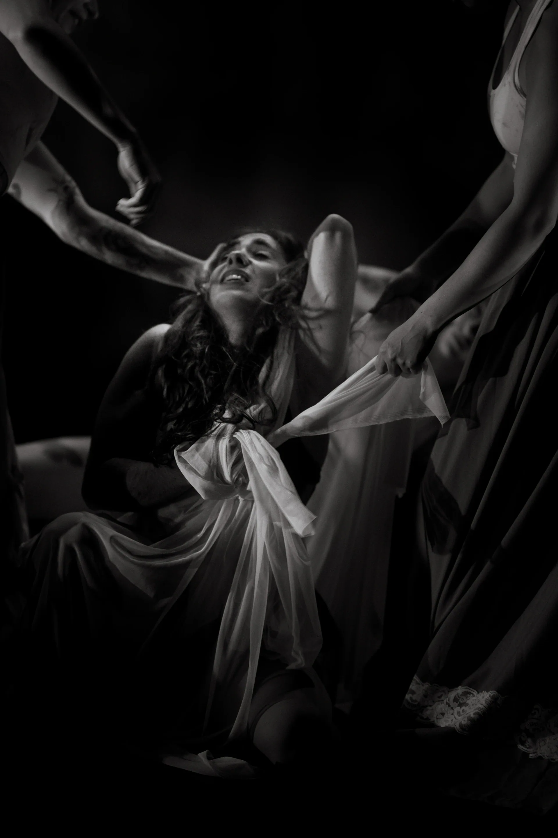 Group of performers reaches upward around a central figure.