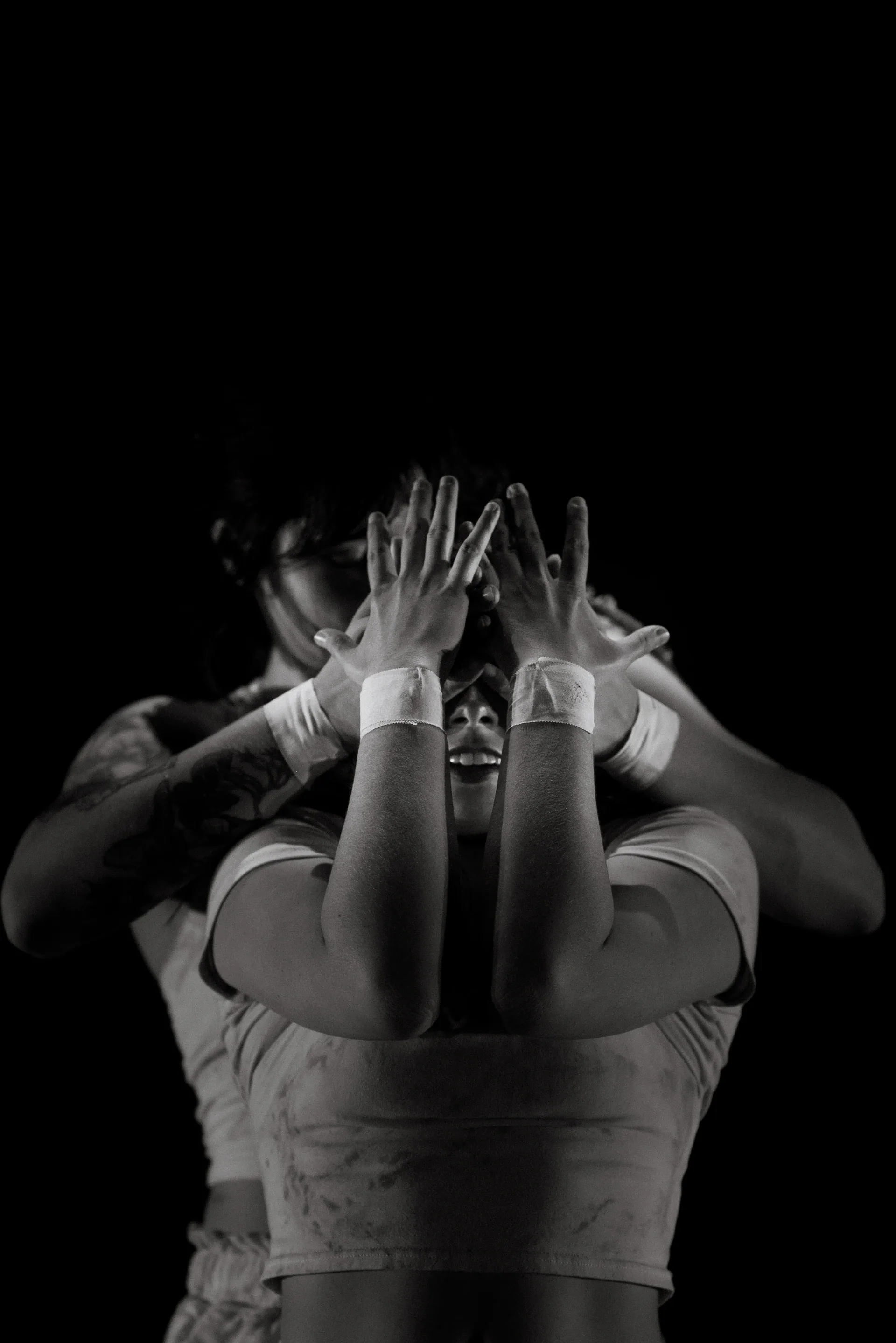 Several hands cover the face of a standing performer.