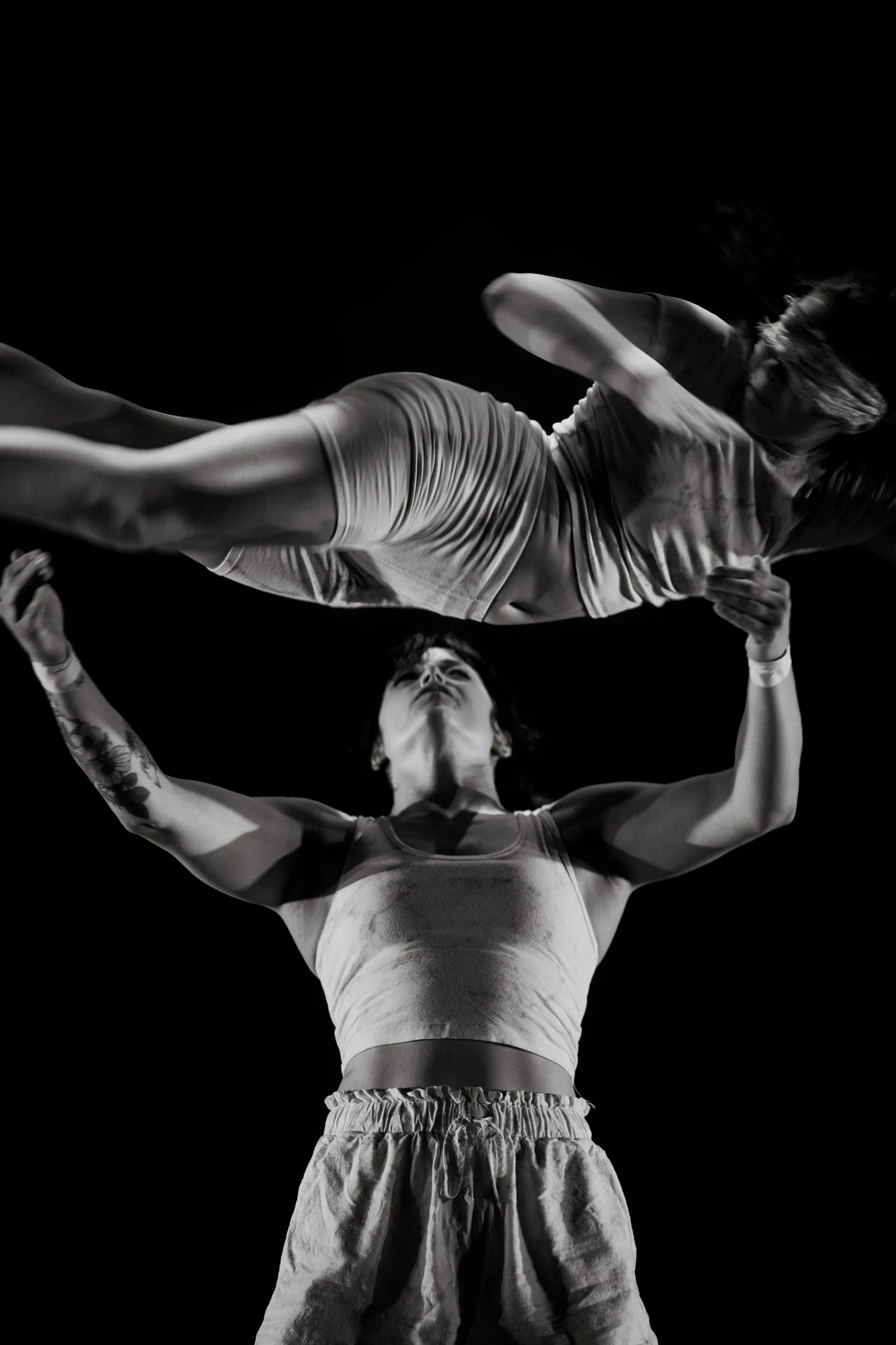 One performer balances another horizontally on raised feet.
