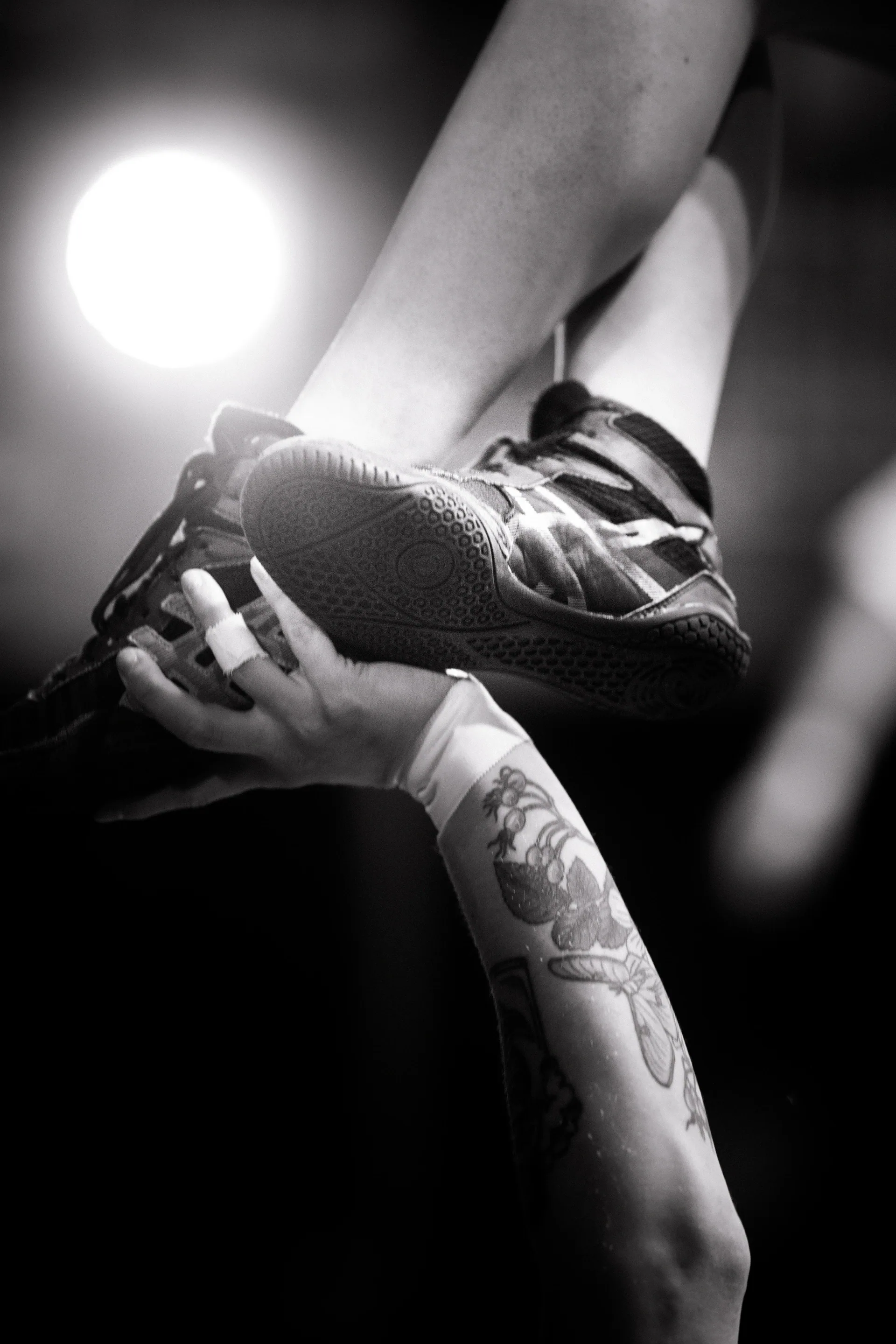 Close view of hands supporting a laced shoe and foot.