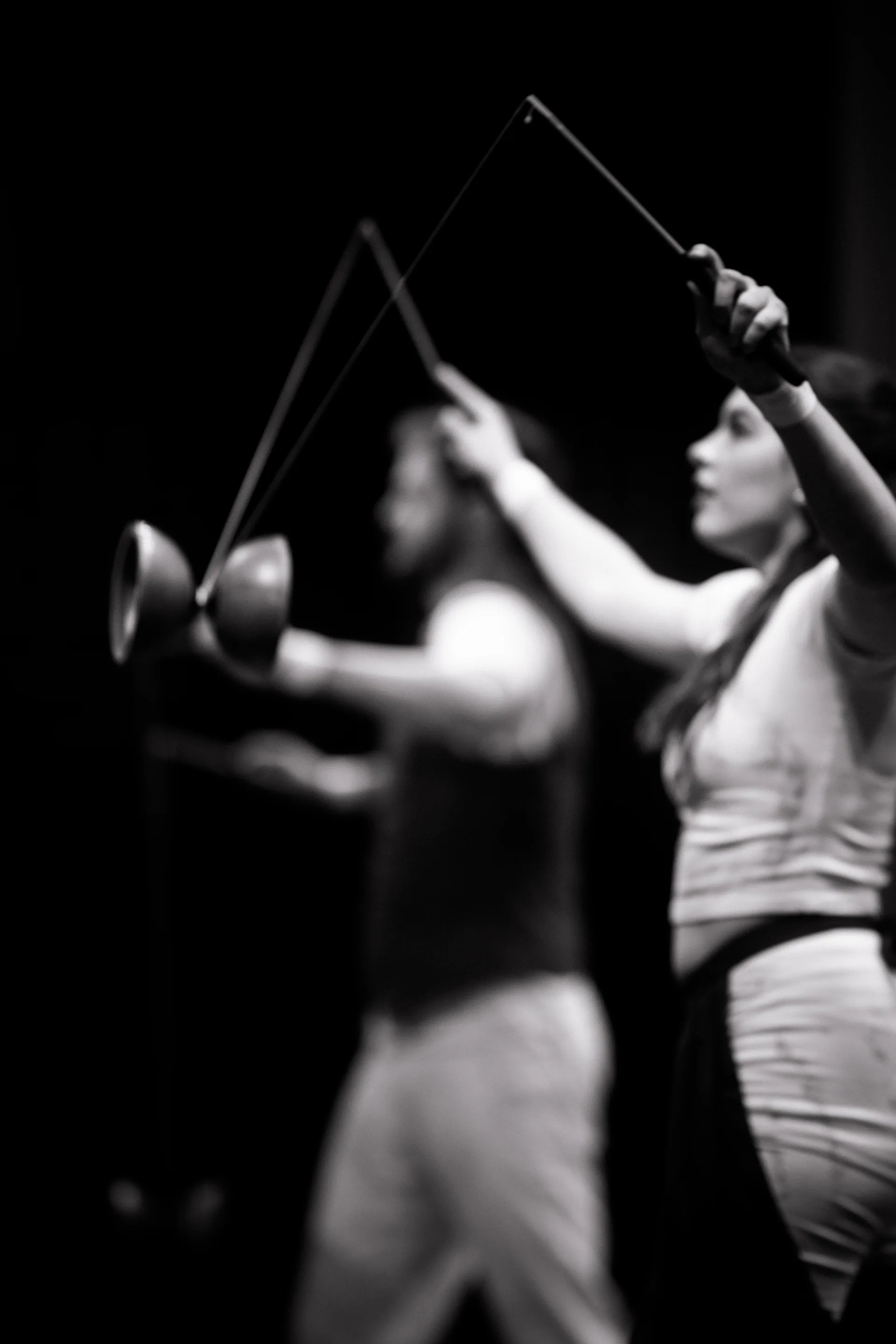 Performer manipulates two diabolo props on crossed strings.