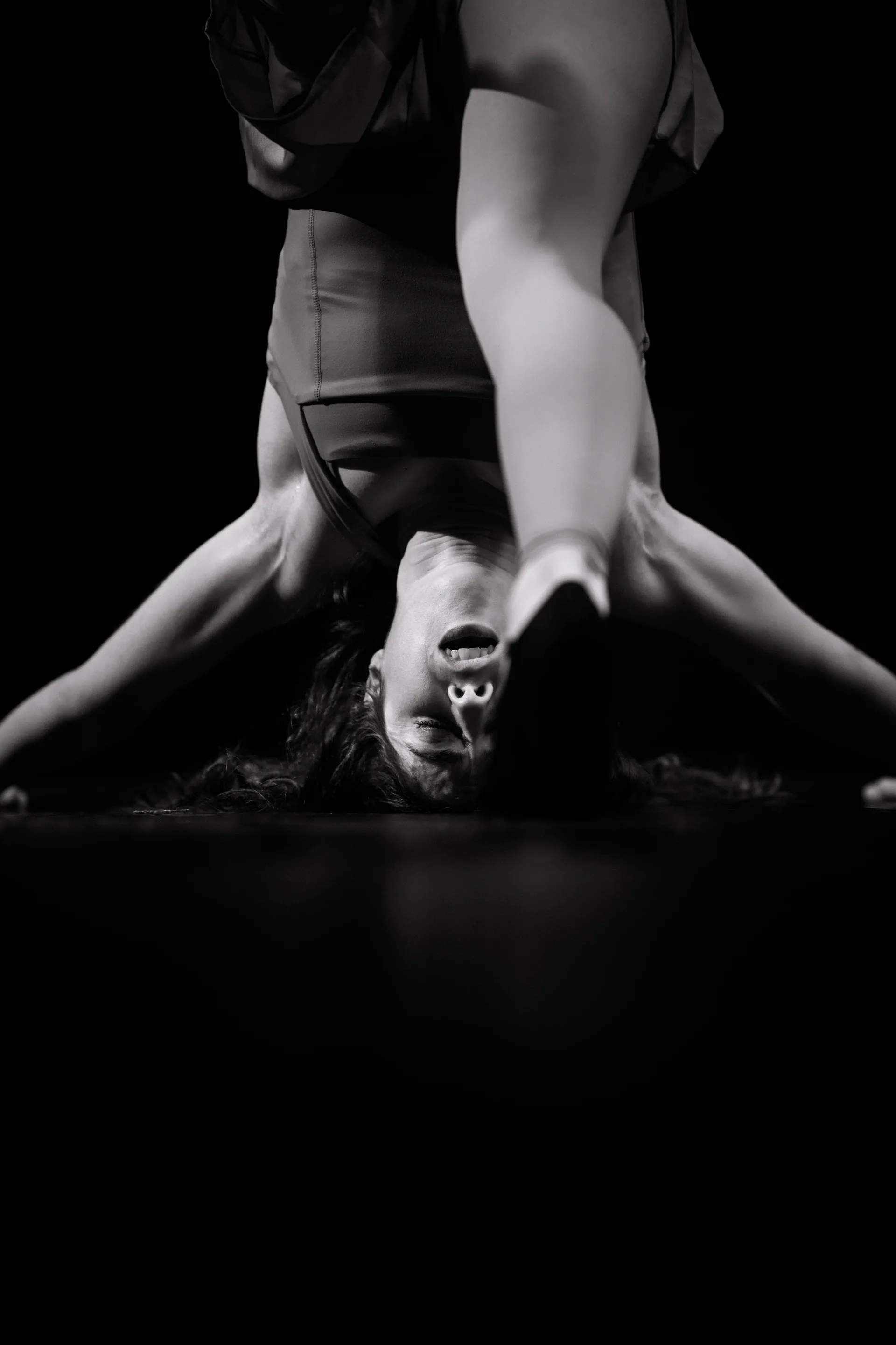 Upside-down performer is supported close to the stage floor.