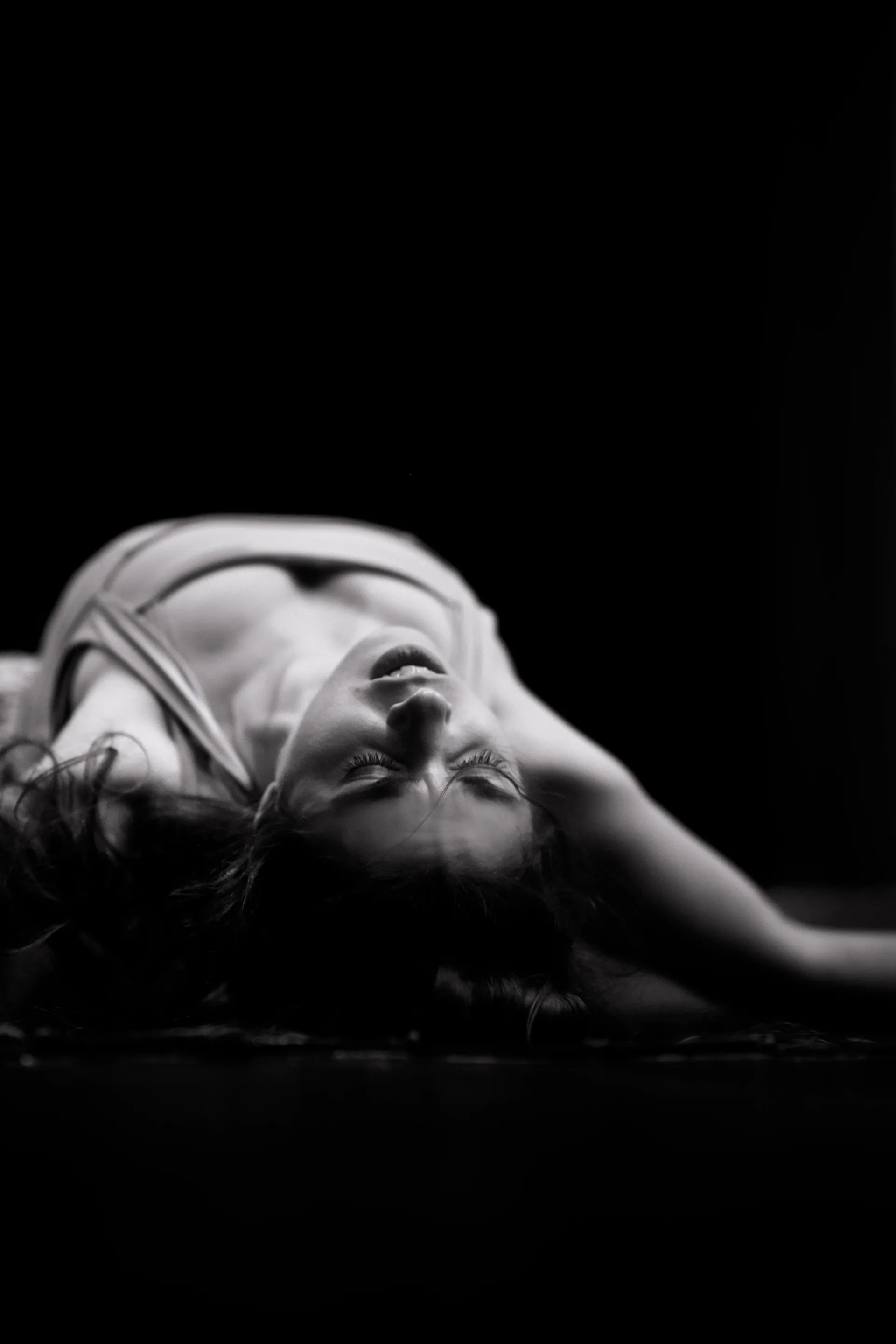 Performer lies in a deep arch with head and shoulders on the floor.