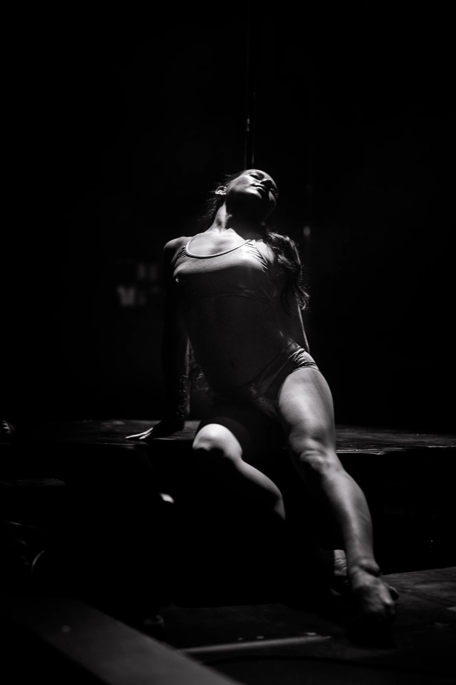 Dancer in a leotard leans backward near the edge of the stage.