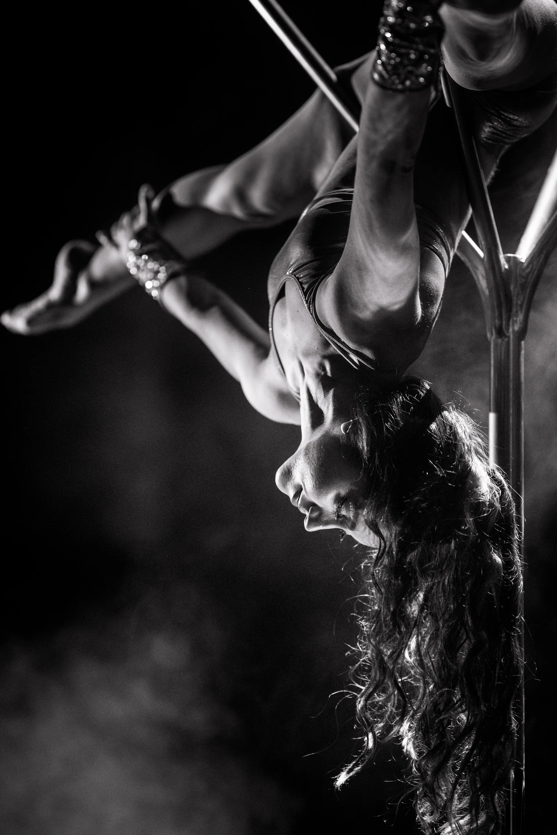Close view of an aerialist hanging upside down from a metal apparatus.