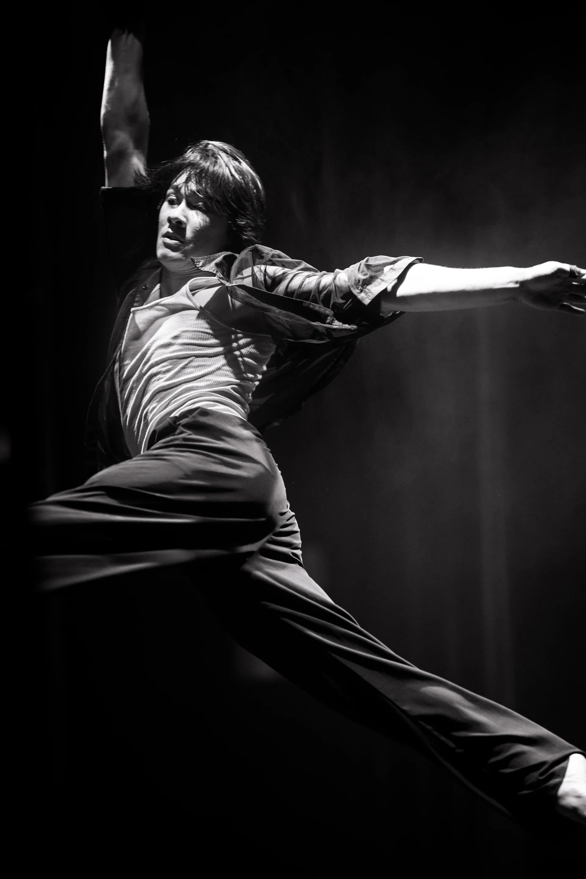 Dancer lunges across the stage with one arm extended.