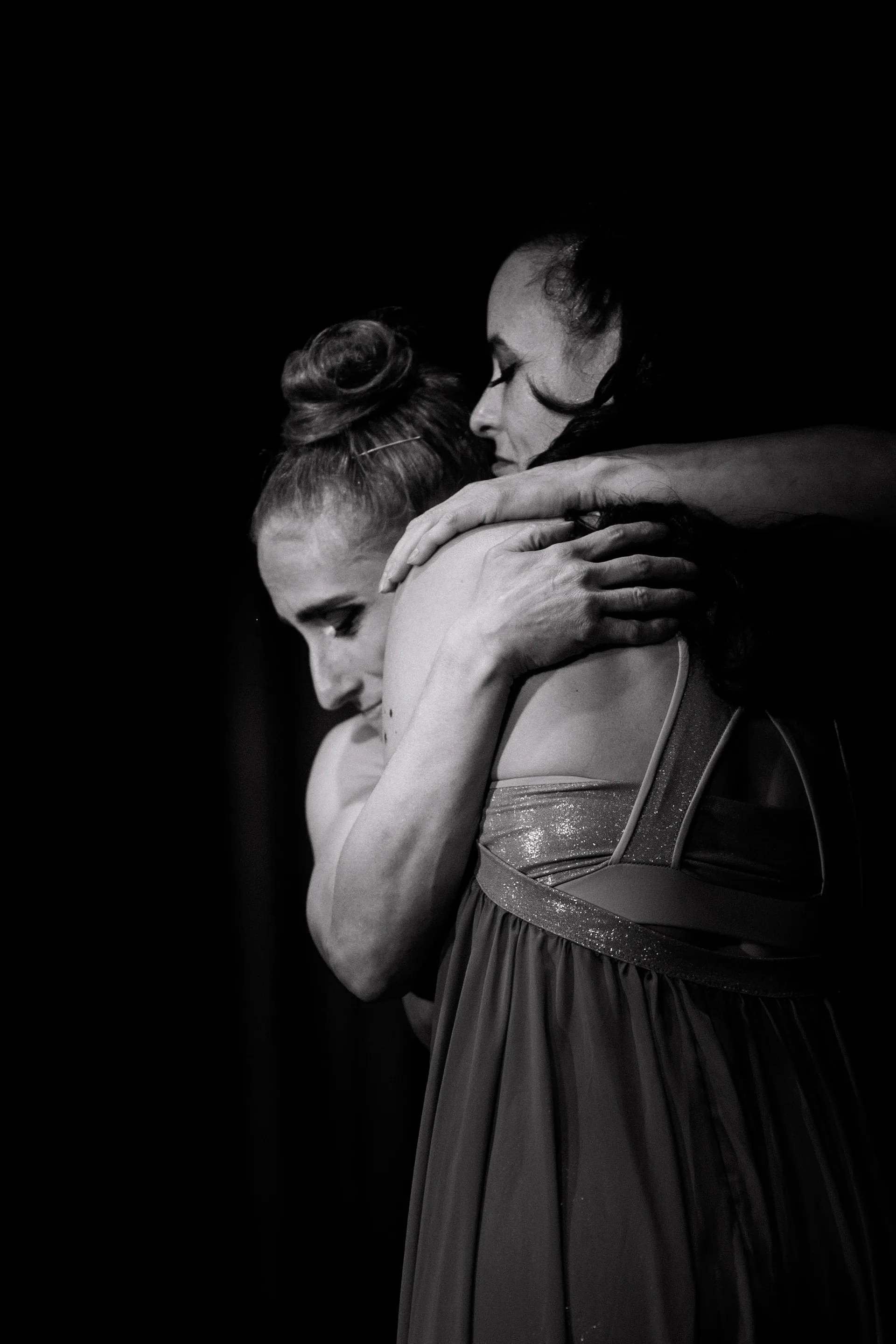 Two performers embrace with one looking downward.